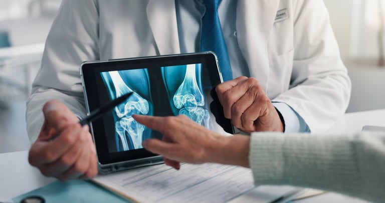 Hands, doctor and tablet for x ray with knee, scan or osteoporosis with point at hospital. People, application and ux for medical consultation for arthritis, feedback or report for wellness at clinic