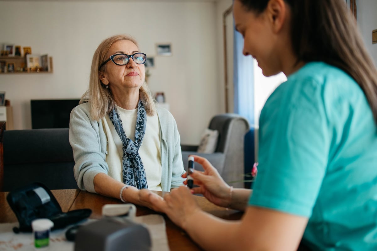 Doctor checks senior woman's blood sugar at home